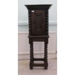 A late 19thC oak cabinet-on-stand with a panelled door, raised on bobbin turned supports and casters