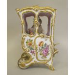 A late 19thC Bavarian porcelain miniature sedan chair, carrying a woman in formal dress, overpainted