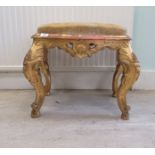 A late 19th/early 20thC carved giltwood framed Continental stool of shaped outline, the old gold