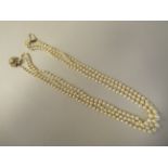 A graduated three row pearl necklace, on a 9ct gold rosette clasp