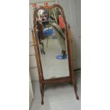 A 1930s Queen Anne style walnut framed cheval mirror with a moulded apron, raised on splayed legs