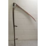 An early 20thC scythe with a cast iron blade and an oak handgrip