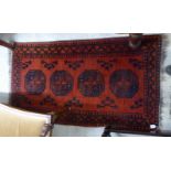 A Turkoman rug, decorated with a column of four octagonal guls on a red ground  33" x 60"