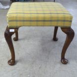 A 1930s Queen Anne style stained beech framed stool with a yellow fabric upholstered top, raised