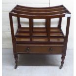 A mid Victorian mahogany Canterbury with a base drawer, raised on turned legs and brass casters