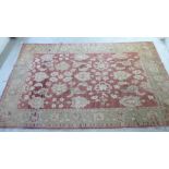 A Caucasian rug with floral motifs, on a terracotta coloured and beige ground  106" x 69"