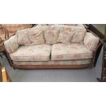 A modern Ercol Renaissance elm and oak framed three person settee with floral patterned cushions