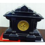 A late Victorian black slate cased mantel clock of breakfront, architectural form; the movement