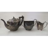 An early 20thC silver three piece tea set of oval demi-reeded form  comprising a teapot, sugar basin