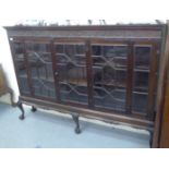 A 1920s mahogany dwarf bookcase with a level top and blint fret carved frieze, over astragal