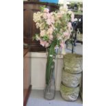 A modern clear glass floorstanding vase of cylindrical form  33"h with an arrangement of faux