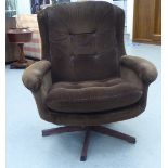 A late 1960s/early 1970s brown fabric upholstered chair, raised and rotating on a faux rosewood base