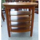 A modern mahogany four tier oval occasional table with a rotating top, raised on square legs  25"
