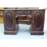 A late Victorian design mahogany desk with a marble top, over a drawer and two cupboard doors, on