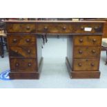 A late Victorian walnut nine drawer, twin pedestal desk, the top with an inset scriber, on