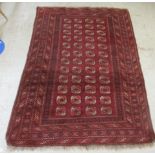 A Bokhara rug, decorated with four columns of twelve octagonal guls, bordered by repeating diamond