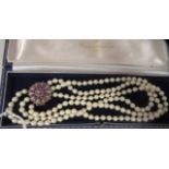 A triple row pearl choker, on a white metal ruby and diamond set rosette clasp