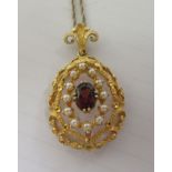 A 9ct textured gold peardrop shaped pendant, set with a coloured stone and seed pearls, on a fine