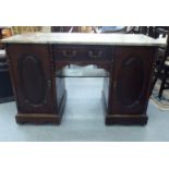 A late Victorian design mahogany desk with a marble top, over a drawer and two cupboard doors, on