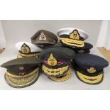 Nine various unidentified foreign military officers' peaked uniform hats, decorated with emblems