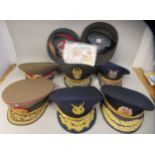 Eight various foreign military officers' peaked uniform hats, decorated with emblems and braid: to
