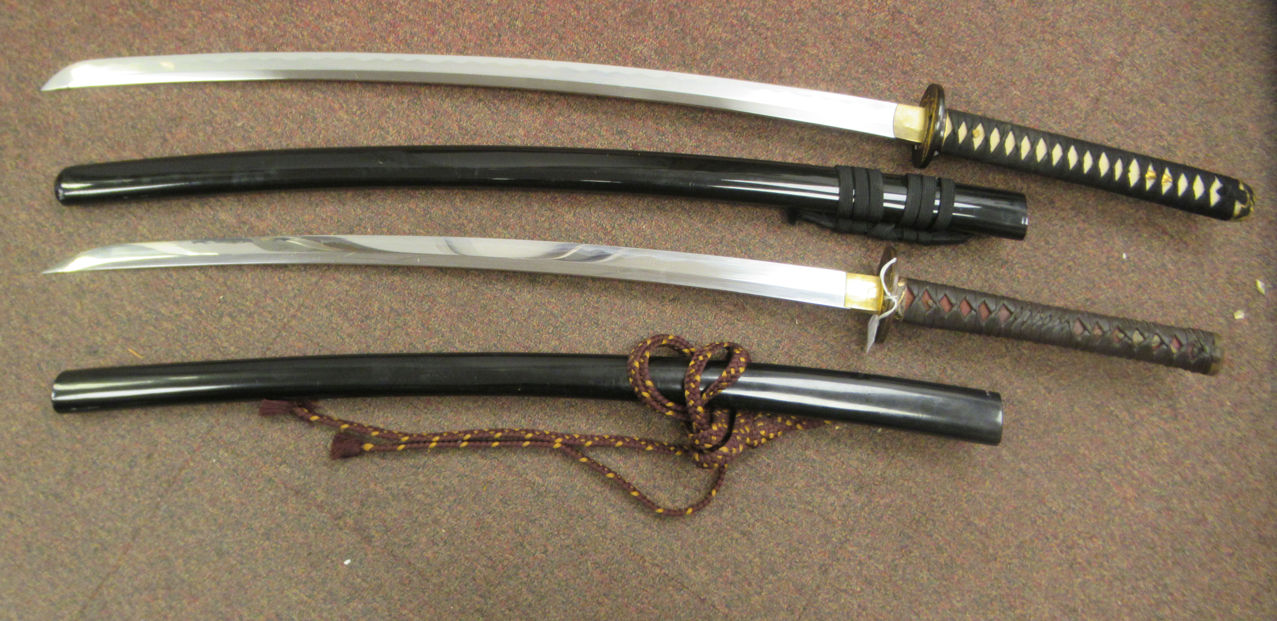 Two similar 20thC Japanese swords with woven fabric bound handles and tsuba, the curved, stainless