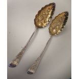 A pair of George III silver and parcel gilt Old English pattern berry spoons with foliate engraved