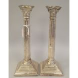 A pair of modern loaded silver candlesticks with detachable bead bordered sconces, Corinthian