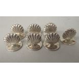 A set of seven silver scallop shell design menu holders, on round stands  T-C  Birmingham 1993