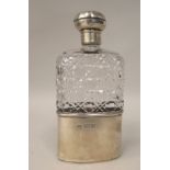 An Edwardian cut glass shouldered hip flask with a silver sleeve cup and threaded mushroom shaped