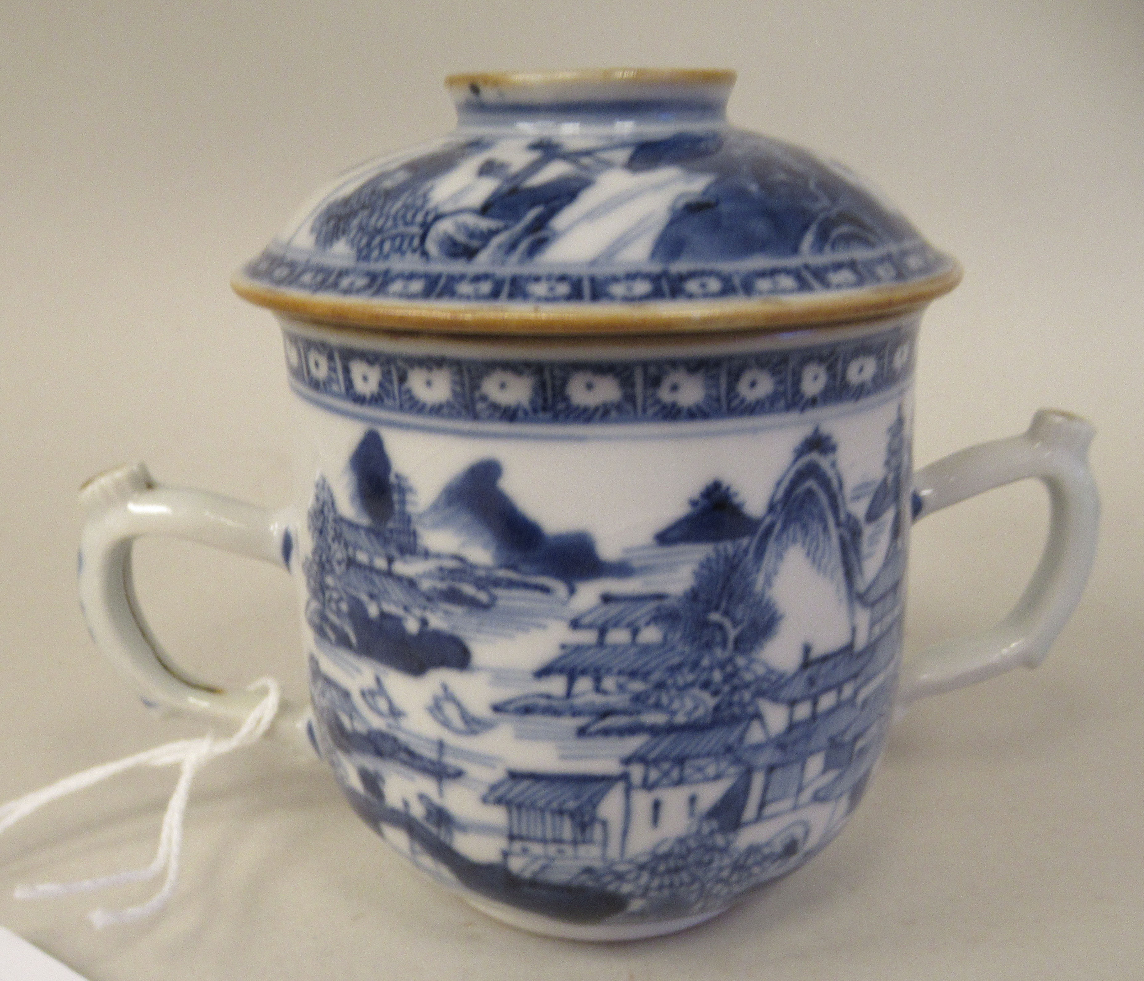 A late 18thC Chinese porcelain twin handled cup and cover, decorated in blue and white with figures,