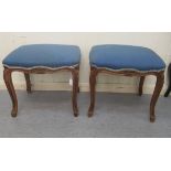A pair of 20thC carved and moulded mahogany framed and upholstered stools of serpentine outline, the