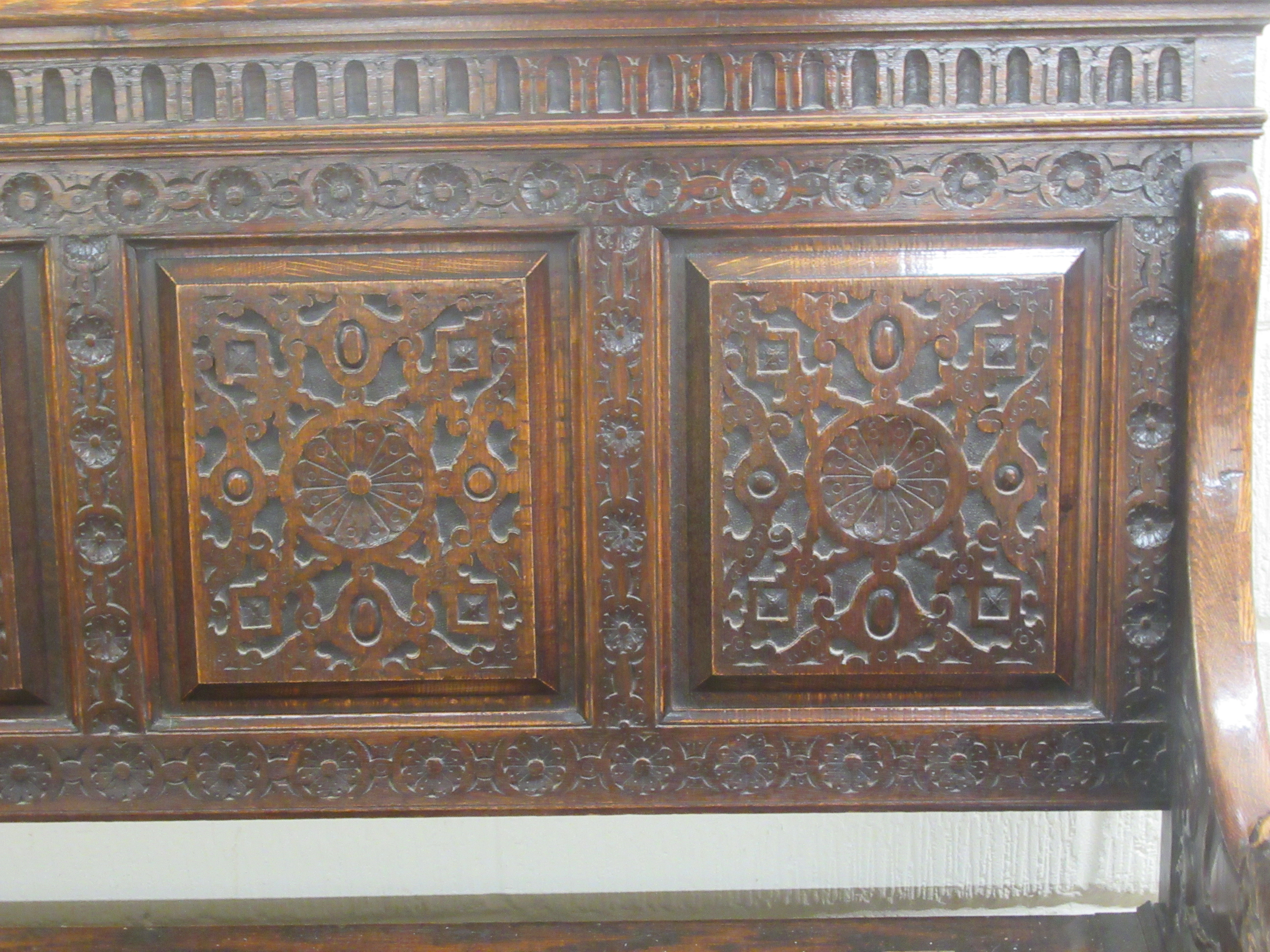A late Victorian profusely carved oak settle with a high, level, quadruple fielded panelled back and - Image 3 of 7