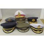 Seven various foreign military officers' peaked uniform hats, decorated with emblems and braid: to