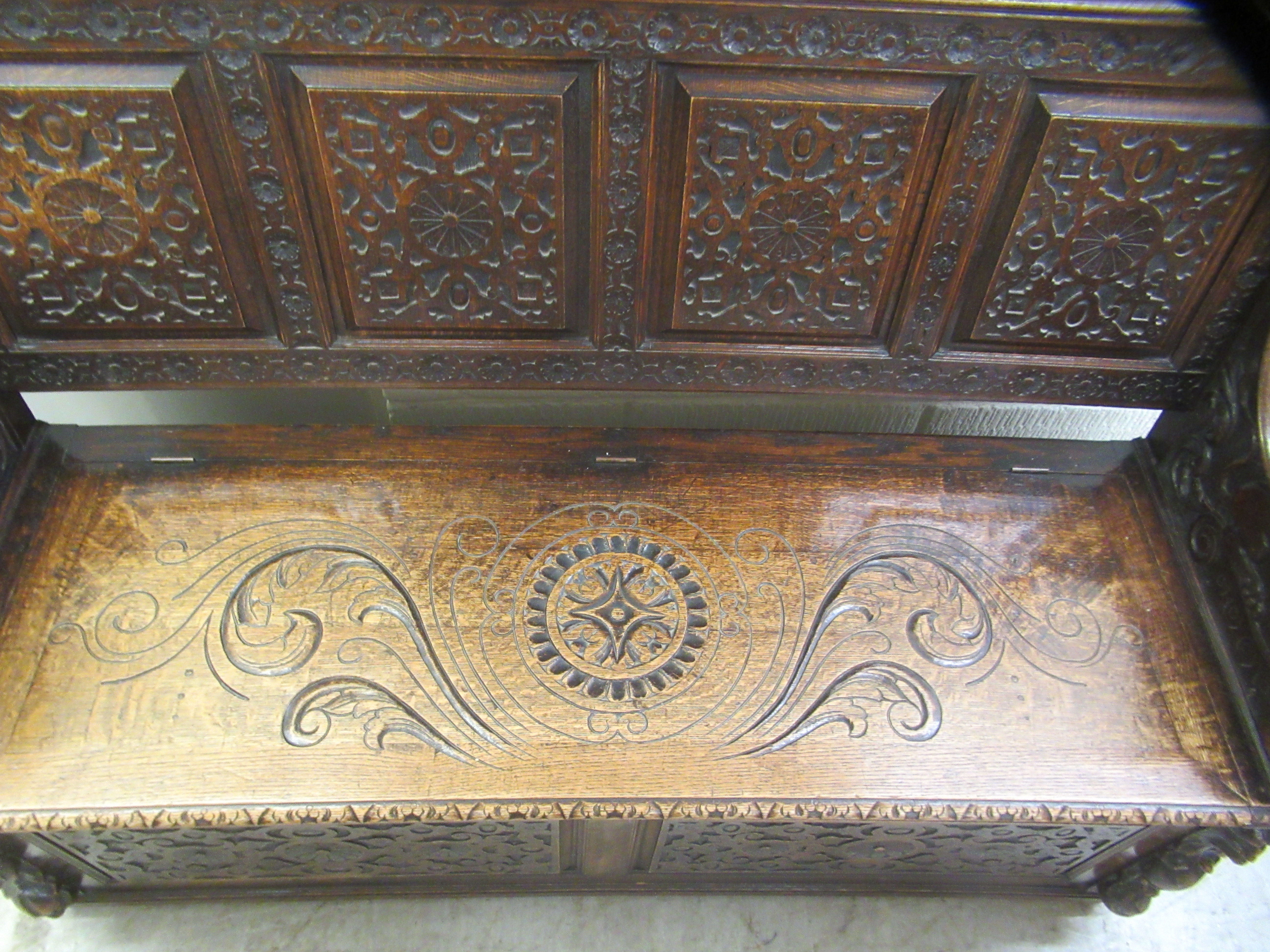 A late Victorian profusely carved oak settle with a high, level, quadruple fielded panelled back and - Image 4 of 7