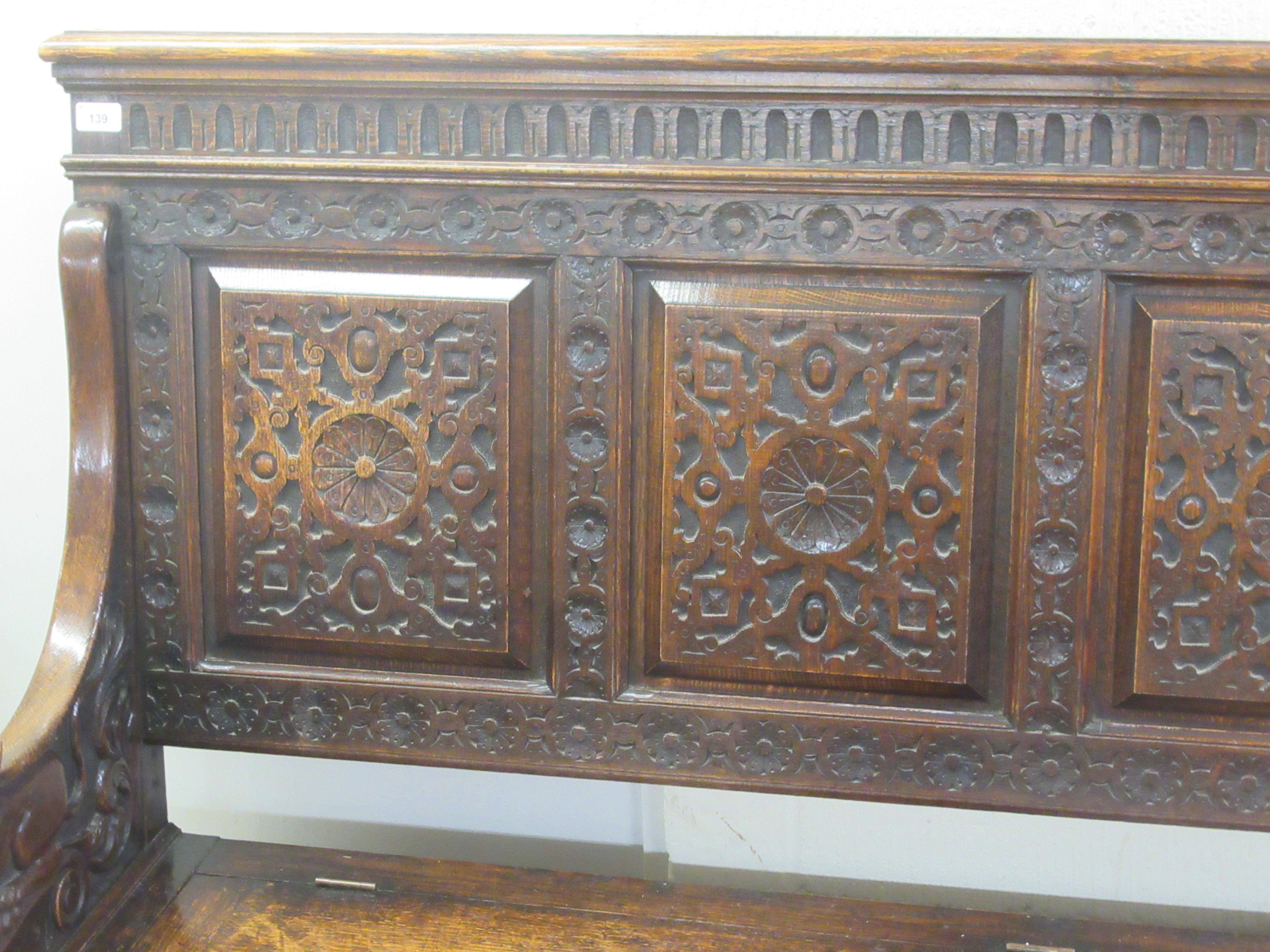 A late Victorian profusely carved oak settle with a high, level, quadruple fielded panelled back and - Image 2 of 7