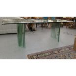 A modern glass dining table, raised on concave pedestals  30"  80"L