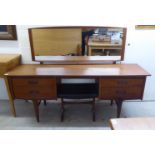 A 1970s teak dressing table surmounted by a rectangular mirror, over four drawers, raised on tapered