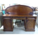 A mid Victorian mahogany twin pedestal sideboard, the round, scroll carved back, over three