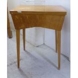 A mid 20thC light oak cased sewing table, raised on square, tapered legs  31"h  24"w incorporating a