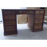 An early 20thC mahogany nine drawer twin pedestal office desk with cast brass bail handles, on