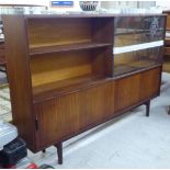 A 1970s 'Multi-Width' teak bookcase with sliding glazed and doors, raised on tapered legs  bears a