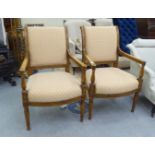 A pair of modern mahogany framed salon chairs with beige fabric upholstered backs and seats,