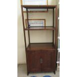 A modern Asian influenced mahogany three tier stand, on square section supports and a base cupboard,