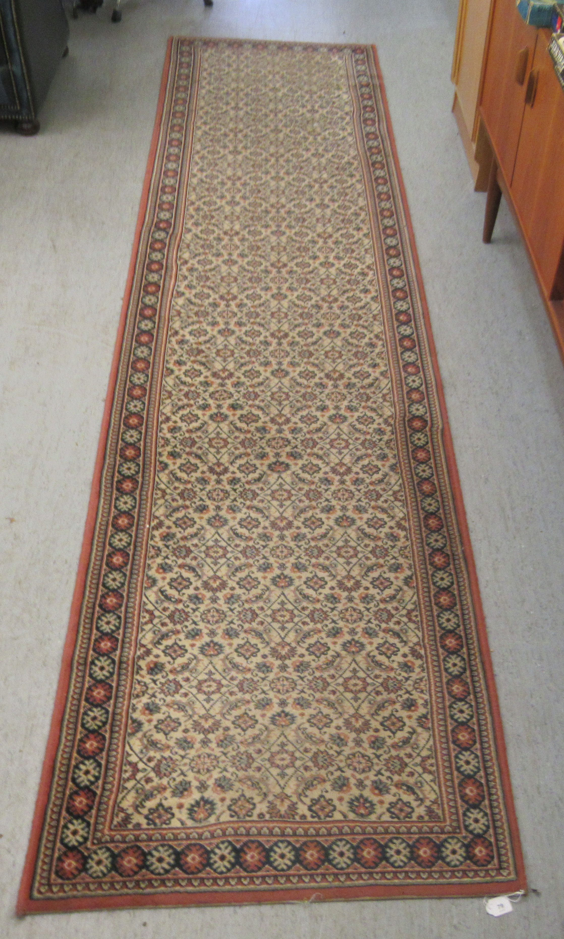 A machine made Persian design runner, decorated with repeating floral designs, on a multi-coloured