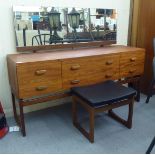 A G-Plan teak dressing table, the unframed tilting mirror over six short and long drawers, raised on