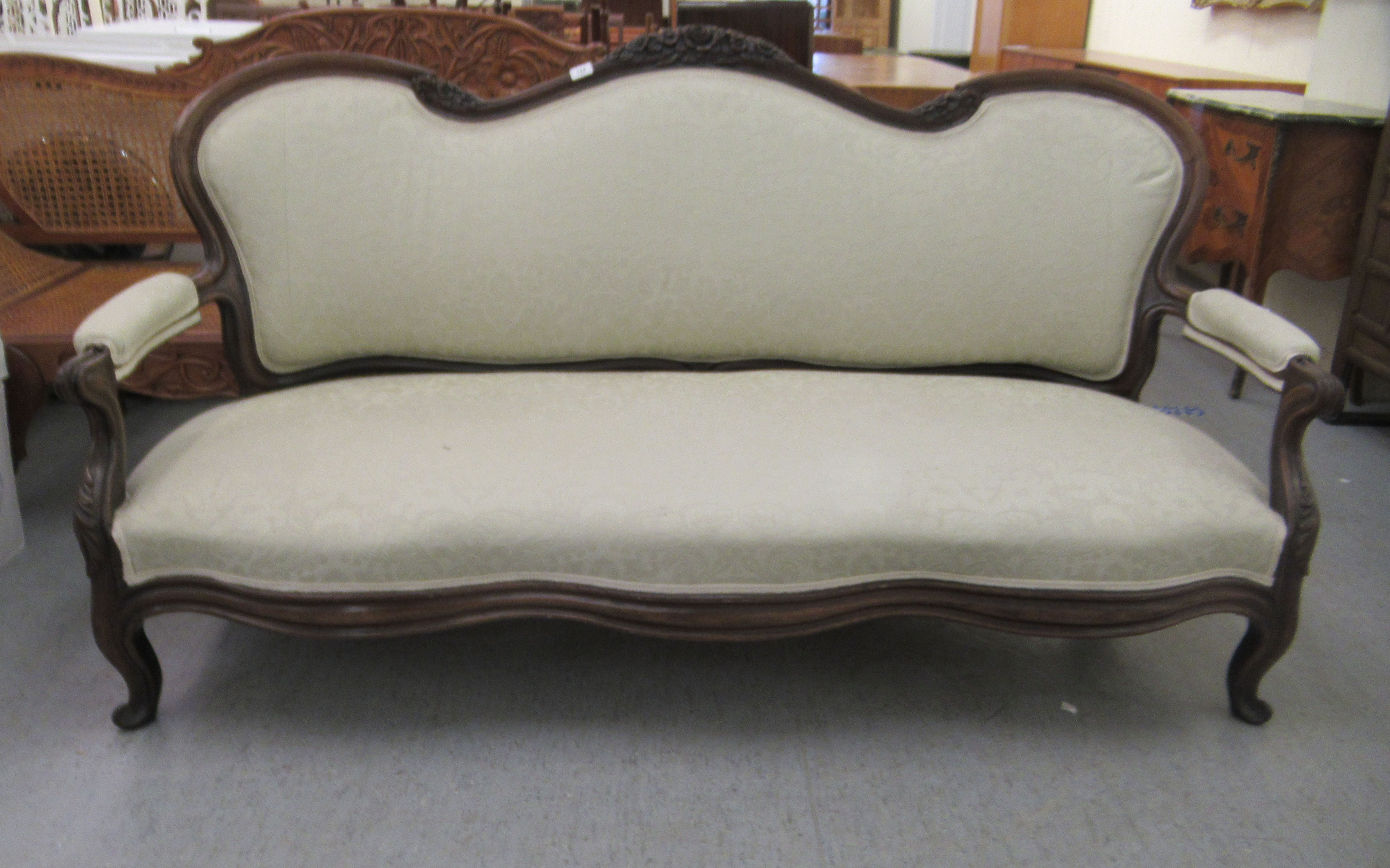 A late Victorian mahogany framed salon settee with a grey fabric upholstered back and seat, raised