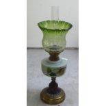 A late Victorian oil lamp with a brass burner and a floral painted glass reservoir, on a turned