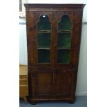 An early 20thC Georgian design walnut corner cabinet with a pair of glazed doors, over a pair of