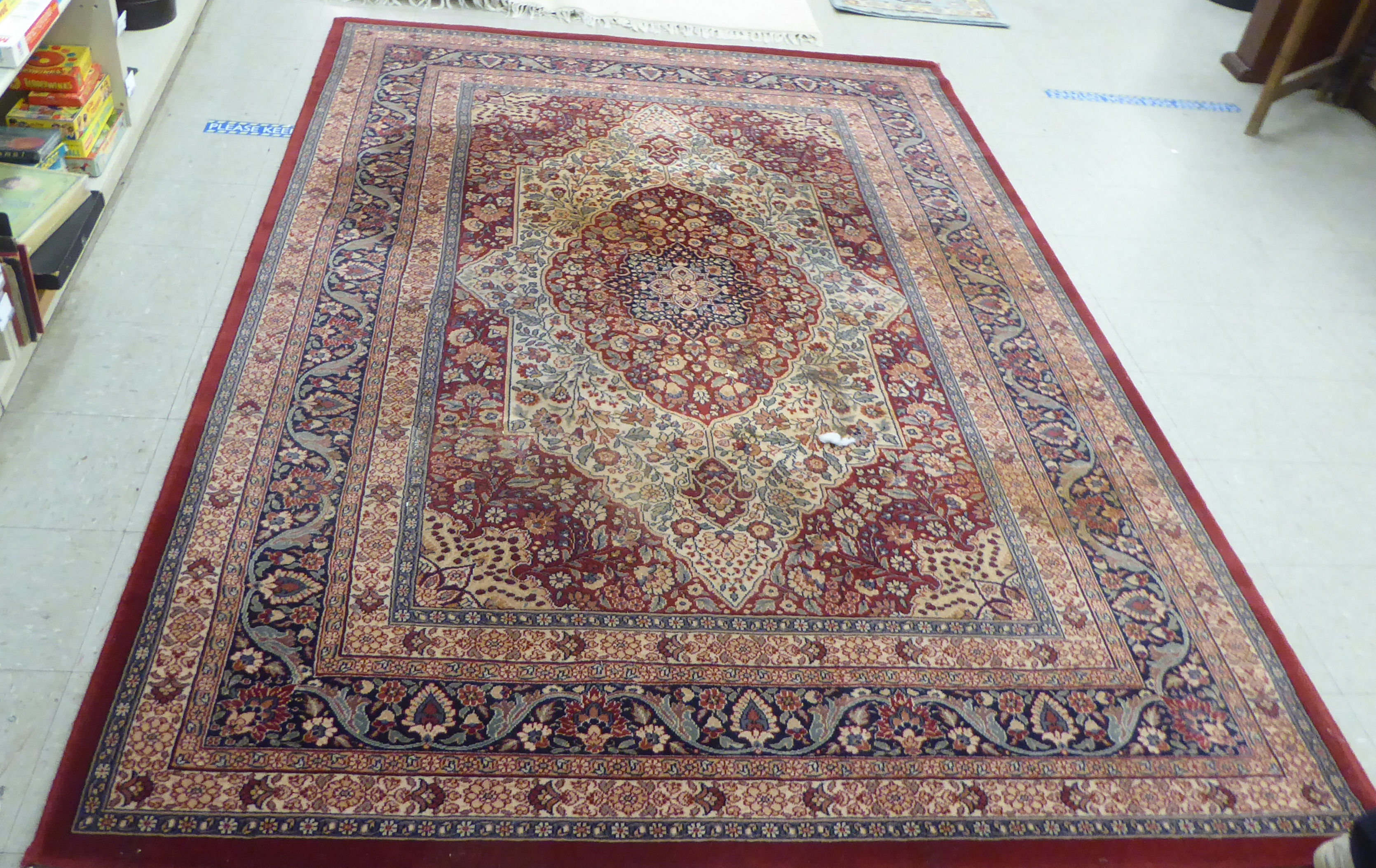 A modern Persian design machine made rug, decorated with flora in bright colours, on a red ground